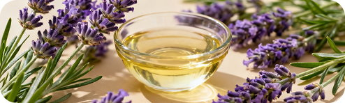 Lavender sprigs beside a bowl of pale oil