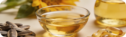 Sunflower seeds beside a bowl of golden oil